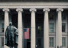 Fed Signals Longer Pain as Rate Cut Hopes Fade US Treasury Department building with statue and flag.