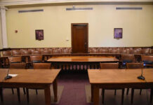 Warrantless Spying Showdown Erupts Empty courtroom with wooden tables, chairs, and a door.