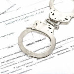 Los Angeles Crime Nightmare Hits Home Handcuffs on top of an arrest warrant document.
