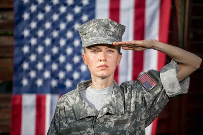 Soldier saluting in front of American flag backdrop.