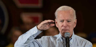 Man holding microphone making a gesture while speaking