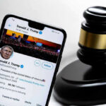 DOJ Backs Down on Compensation Fund Smartphone displaying Twitter profile near a judges gavel.