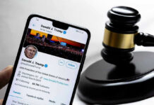 Smartphone displaying Twitter profile near a judges gavel.