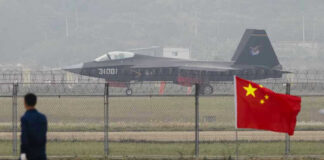 Jet with 31001 marking behind barbed wire fence.