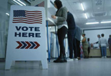 Sign reading Vote Here in a polling station.