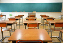 Math Meltdown Alarms Top Professors Empty classroom with desks and a chalkboard.