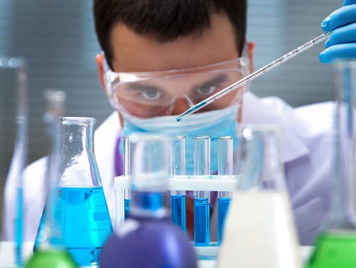 Investigator,Checking,Test,Tubes.,Man,Wears,Protective,Goggles Scientist conducting an experiment with blue liquids in a laboratory