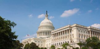 The U.S. Capitol building surrounded by green grass and trees under a blue sky