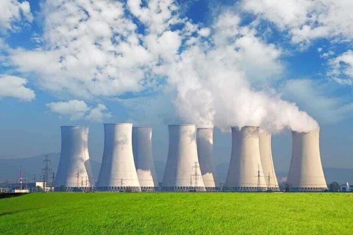 shutterstock_127593578 Nuclear power plant with cooling towers emitting steam against a blue sky