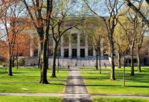 DOJ Sides With Fired Coach Students walking on a university campus with autumn trees and a historic building in the background