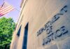 Migrant Child Sponsorship Fraud Exposes System Failures Exterior view of the Department of Justice building with an American flag