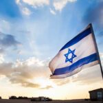 Minister: A Single Quote Could Undo Months of Middle East Diplomacy Israeli flag waving against a sunset backdrop with clouds