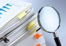 Congress Questions DOJ on Fund and Epstein Docs Stack of documents with a magnifying glass beside it