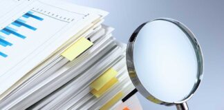Stack of documents with a magnifying glass beside it