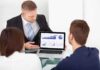 Anthropic Releases AI Model With Safeguards Business professional presenting data on a laptop to two colleagues