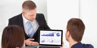 Business professional presenting data on a laptop to two colleagues