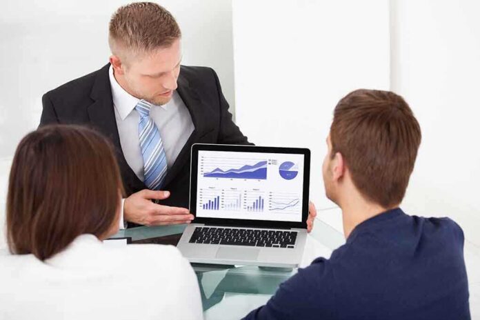 shutterstock_193326596 Business professional presenting data on a laptop to two colleagues