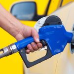 Mystery Crash Near Global Oil Hub Kills 14 A person refueling a car at a gas station with a blue nozzle