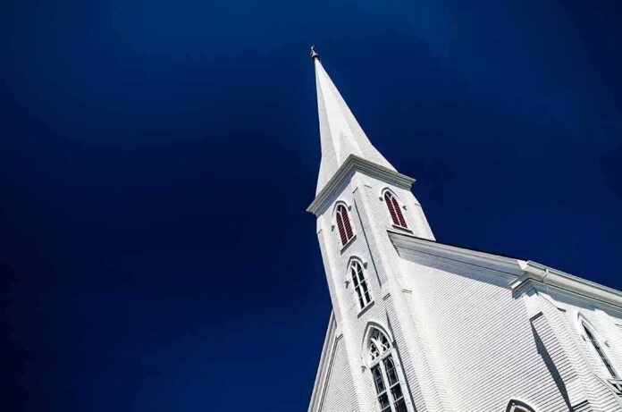 shutterstock_1012717411 White church steeple against deep blue sky