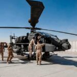 Soldiers inspect a military attack helicopter on a tarmac