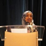 Woman in hijab speaking at a podium