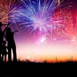 Culture War: Half a Million Gather Under One Flag Silhouetted figures watching a colorful fireworks display against a twilight sky