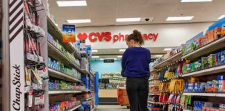 A person shopping in a CVS pharmacy aisle filled with various products