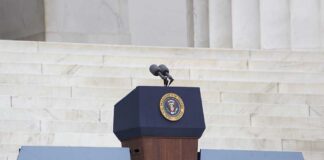 Podium with a microphone and presidential seal in front of steps