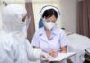 A Deadly Health Alert Is Unfolding in Venezuela nurse in PPE writing on a clipboard with colleague