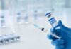 Gloved hands holding a syringe and a vaccine vial