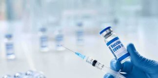 Gloved hands holding a syringe and a vaccine vial