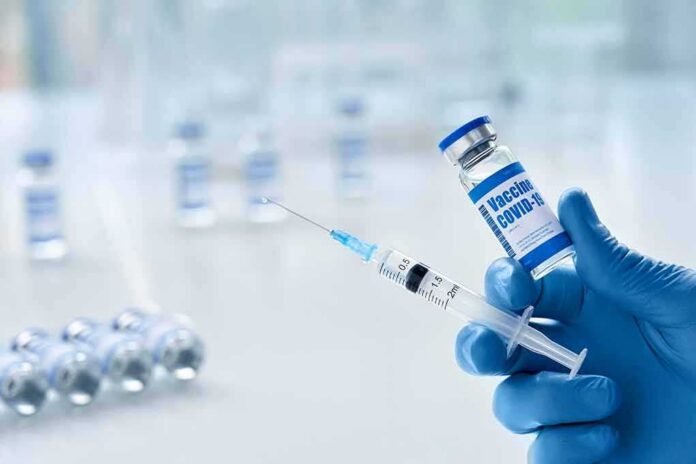 shutterstock_1859998351 Gloved hands holding a syringe and a vaccine vial