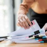 Hands organizing stacked documents with binder clips
