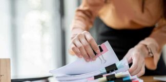 Hands organizing stacked documents with binder clips