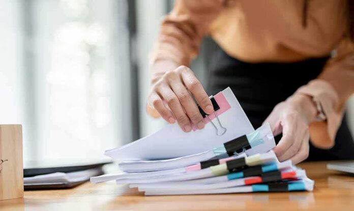 Hands organizing stacked documents with binder clips