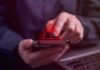 Person tapping smartphone with red warning icon