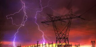 Lightning strikes illuminate a power station against a colorful sunset sky