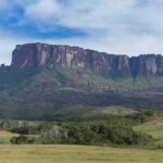Flat-topped mountain rising above green plains under a partly cloudy sky
