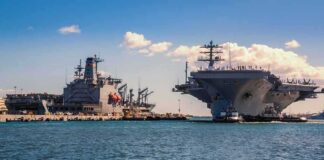 Aircraft carrier and support ships docked at a naval harbor