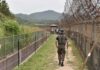Soldier walking along a fenced border path