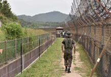 Soldier walking along a fenced border path