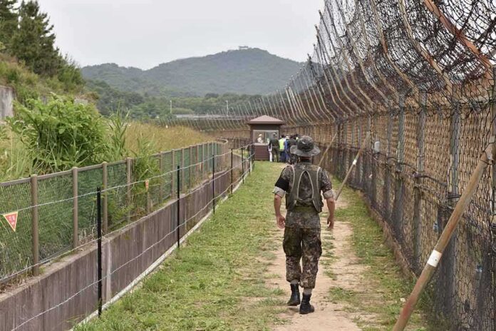 shutterstock_1478361905-1 Soldier walking along a fenced border path