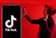 Smartphone displaying TikTok logo with person taking selfie in red light