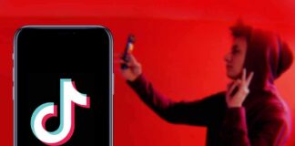 Smartphone displaying TikTok logo with person taking selfie in red light