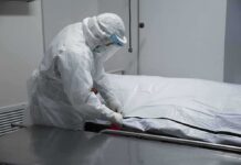 Mexico Church Pushes Dignified Burial for Babies Healthcare worker in PPE zipping a body bag on a gurney