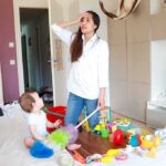 Unlicensed Daycare Operator Faces Multiple Child Abuse Charges Mother standing in messy living room with toddler on couch