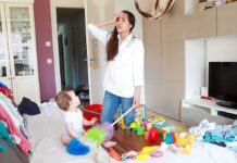 Unlicensed Daycare Operator Faces Multiple Child Abuse Charges Mother standing in messy living room with toddler on couch