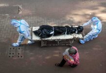 Families Wait as Quake Victims Are Identified health workers in PPE move a body on a stretcher