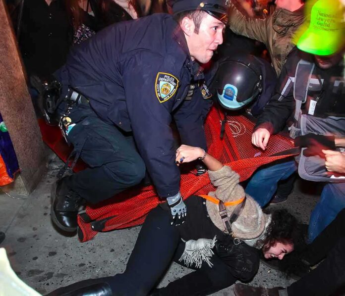 Police officer restraining a protester on the ground during a crowd encounter