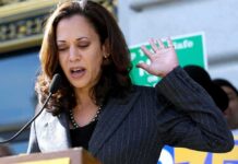Woman speaking at an outdoor podium with hand raised